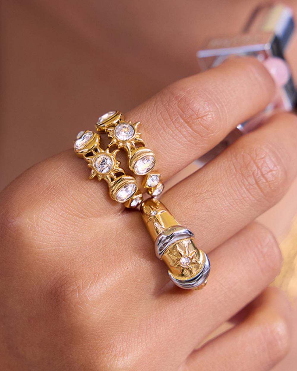 Gold and silver ring with gemstones on a finger