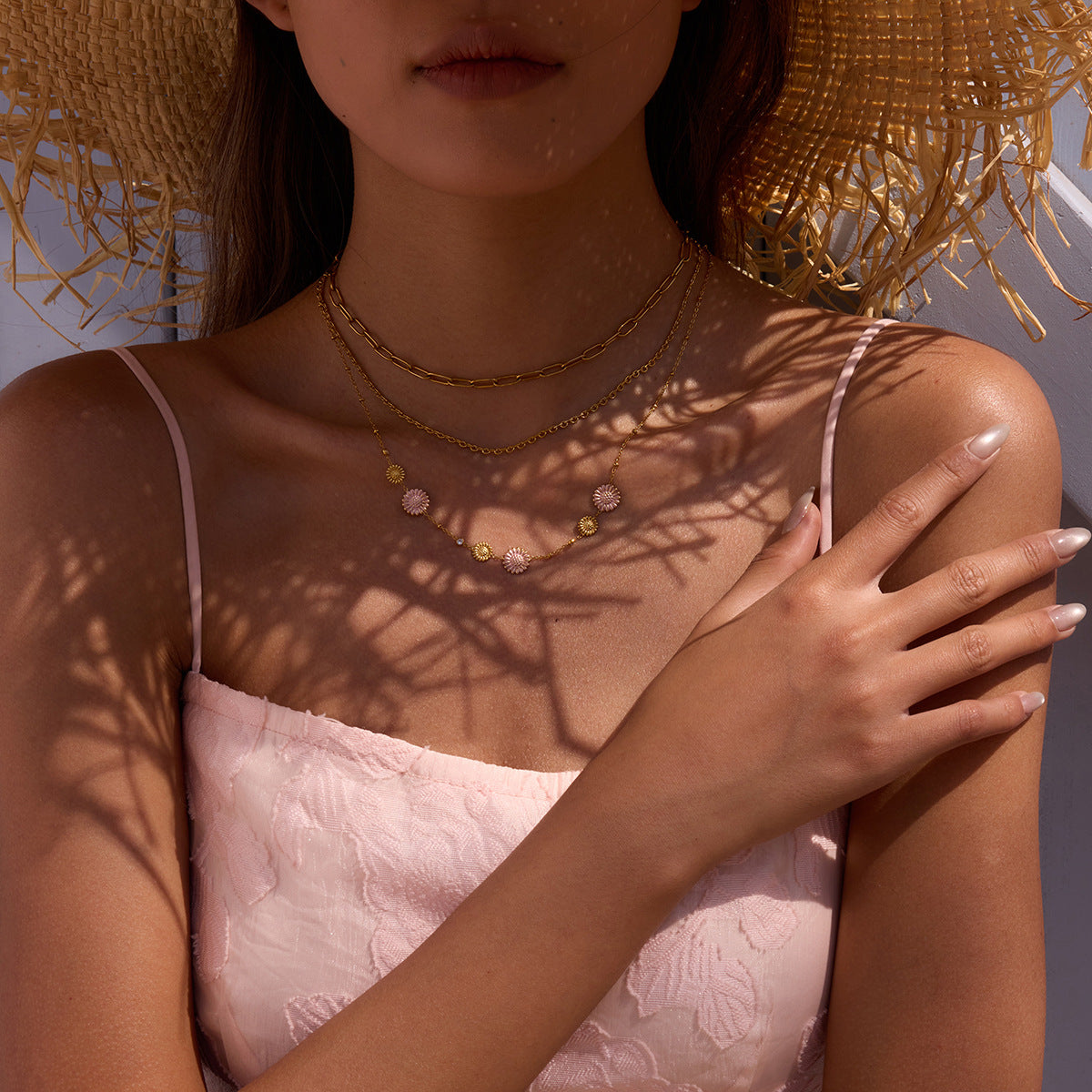 Gold and pink floral necklace styled on magazine with green flowers