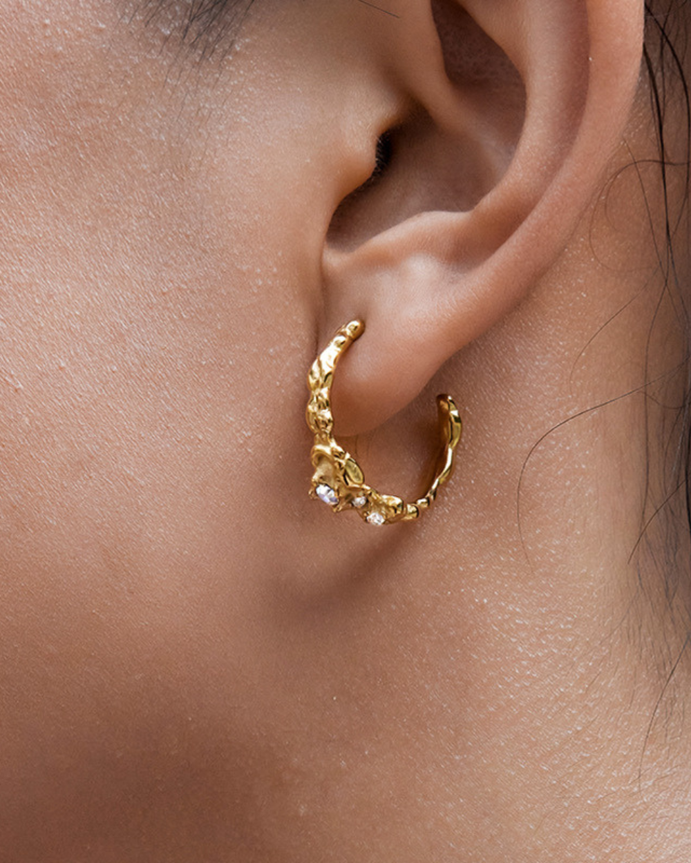 Gold hoop earring worn by a person
