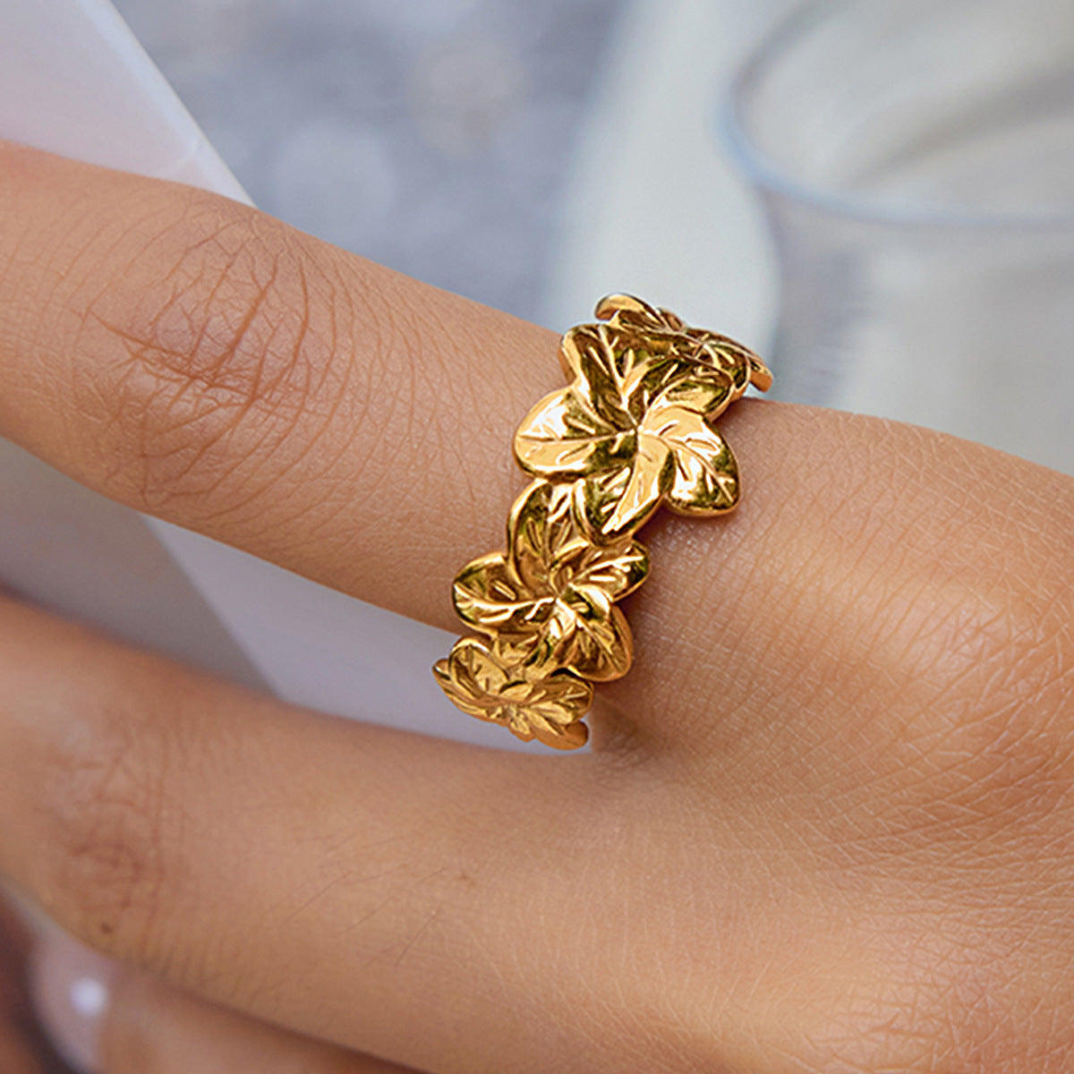 Golden Bloom Ring worn on index finger with glossy gold finish and raised cherry blossom motif