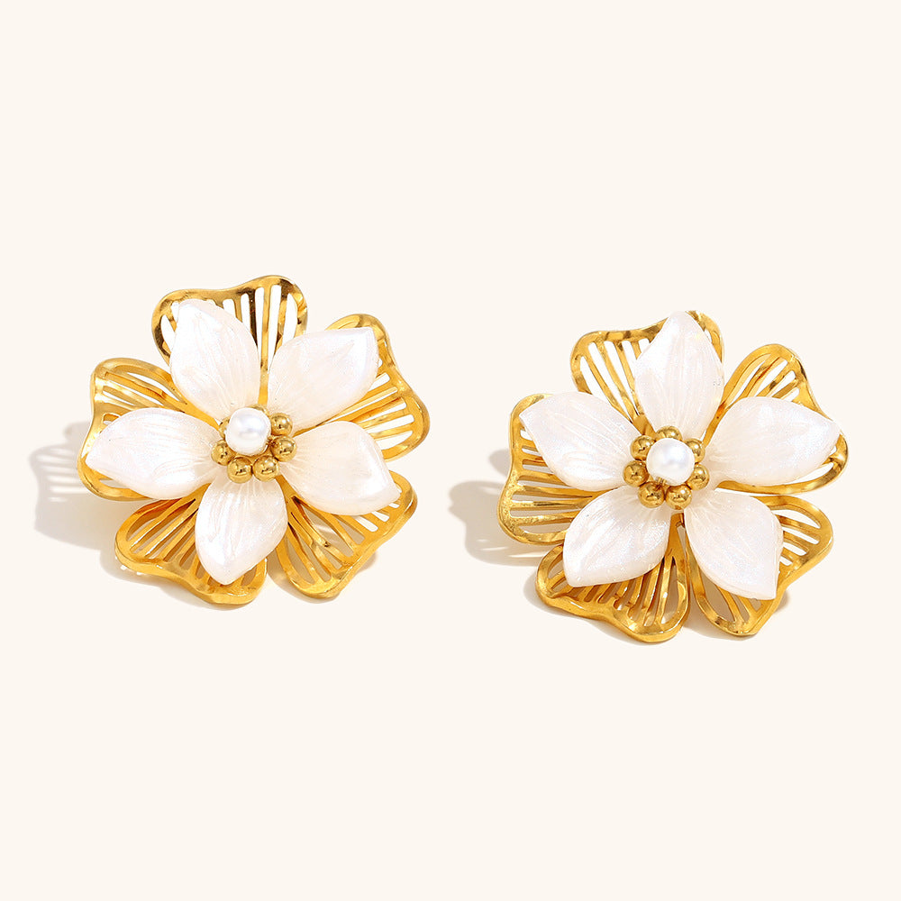 close-up of floral gold and pearl statement earrings on neutral background