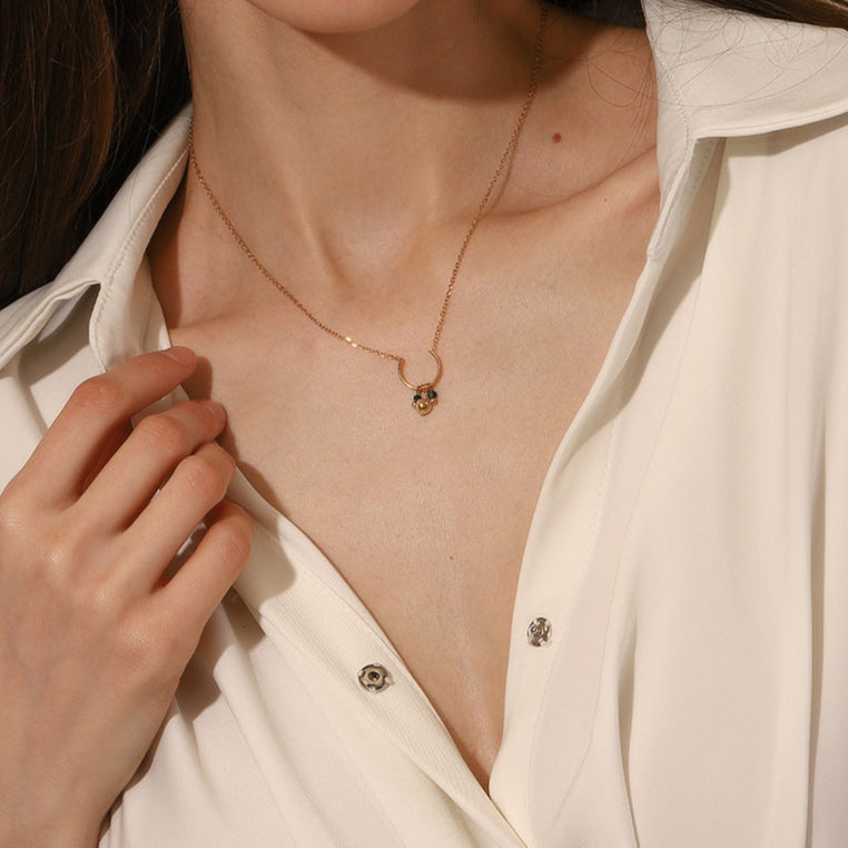 Side profile of model wearing a gold crescent necklace with delicate green details.