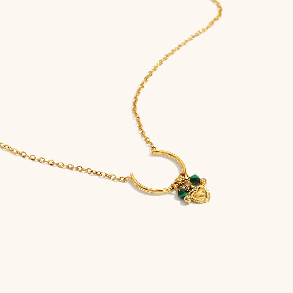 Detailed macro view of gold crescent pendant with green crystal beads and charm.