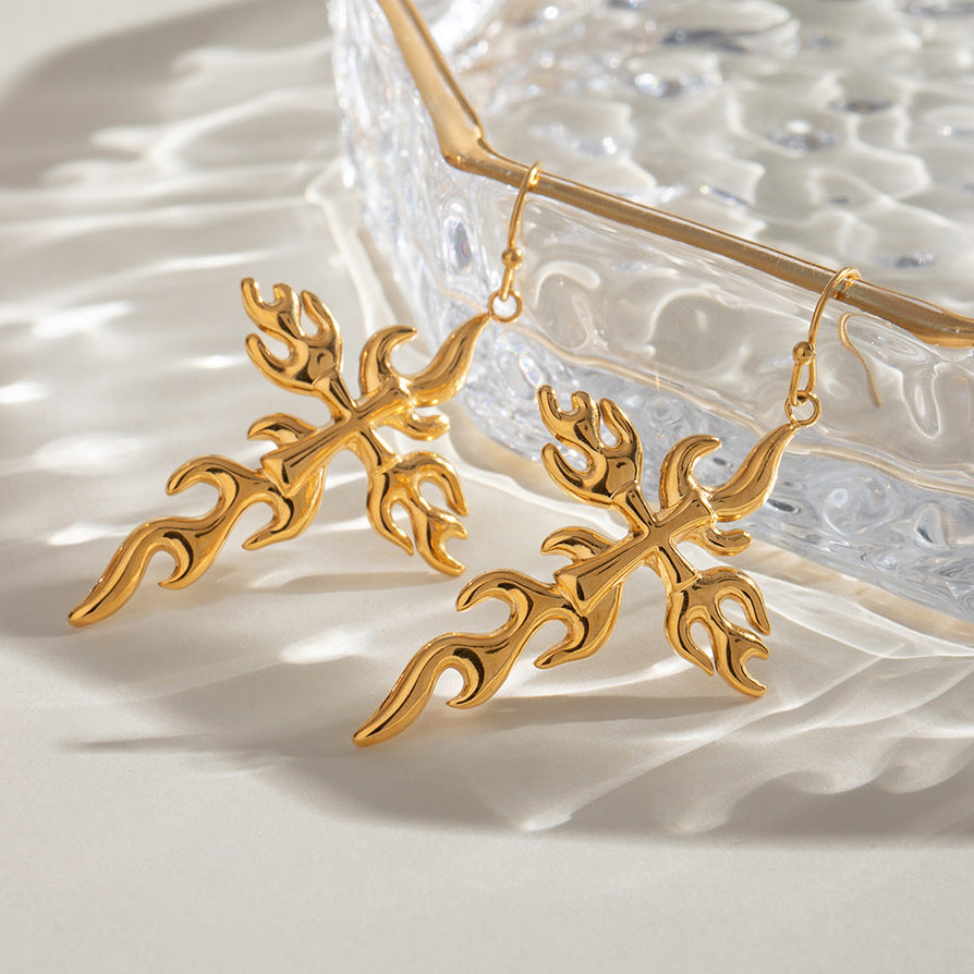 Hand holding large flame earrings with smooth gold plating for daily wear