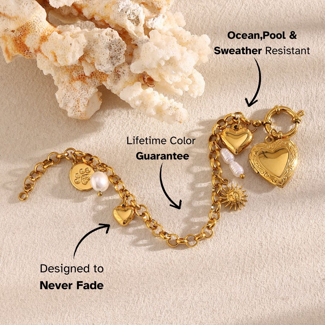 Golden heart charm bracelet laid on sand with ocean coral decor