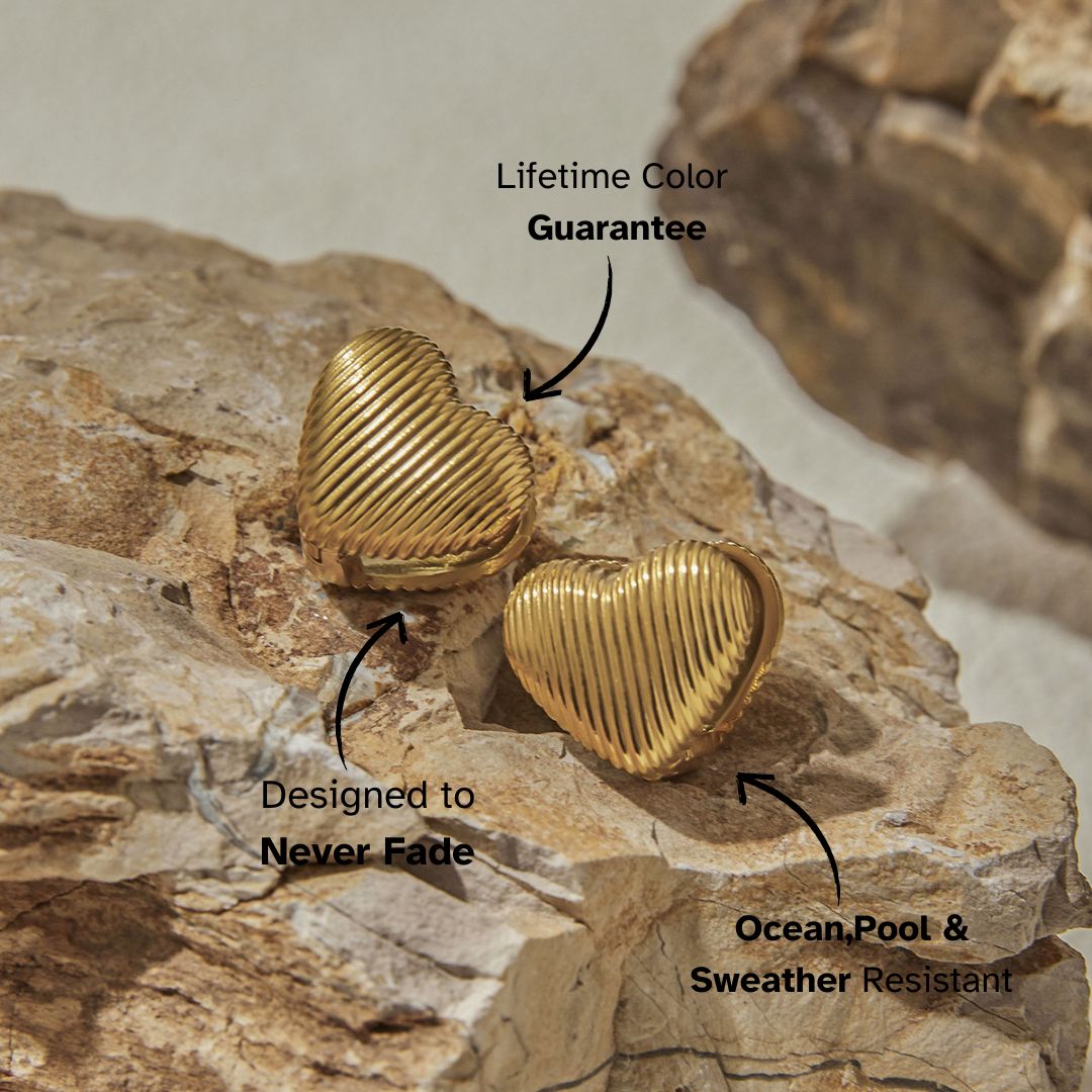 Gold heart-shaped ribbed earrings styled on natural rock surface