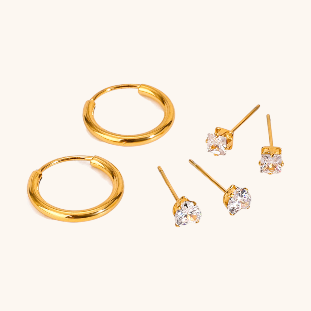 Close-up of shiny gold hoops and brilliant-cut crystal studs on soft beige background