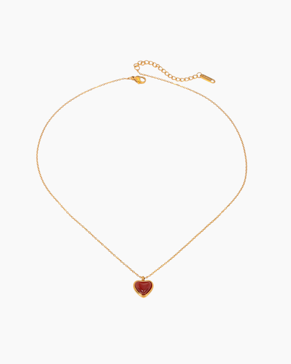 Gold necklace with a heart-shaped red pendant on a white background