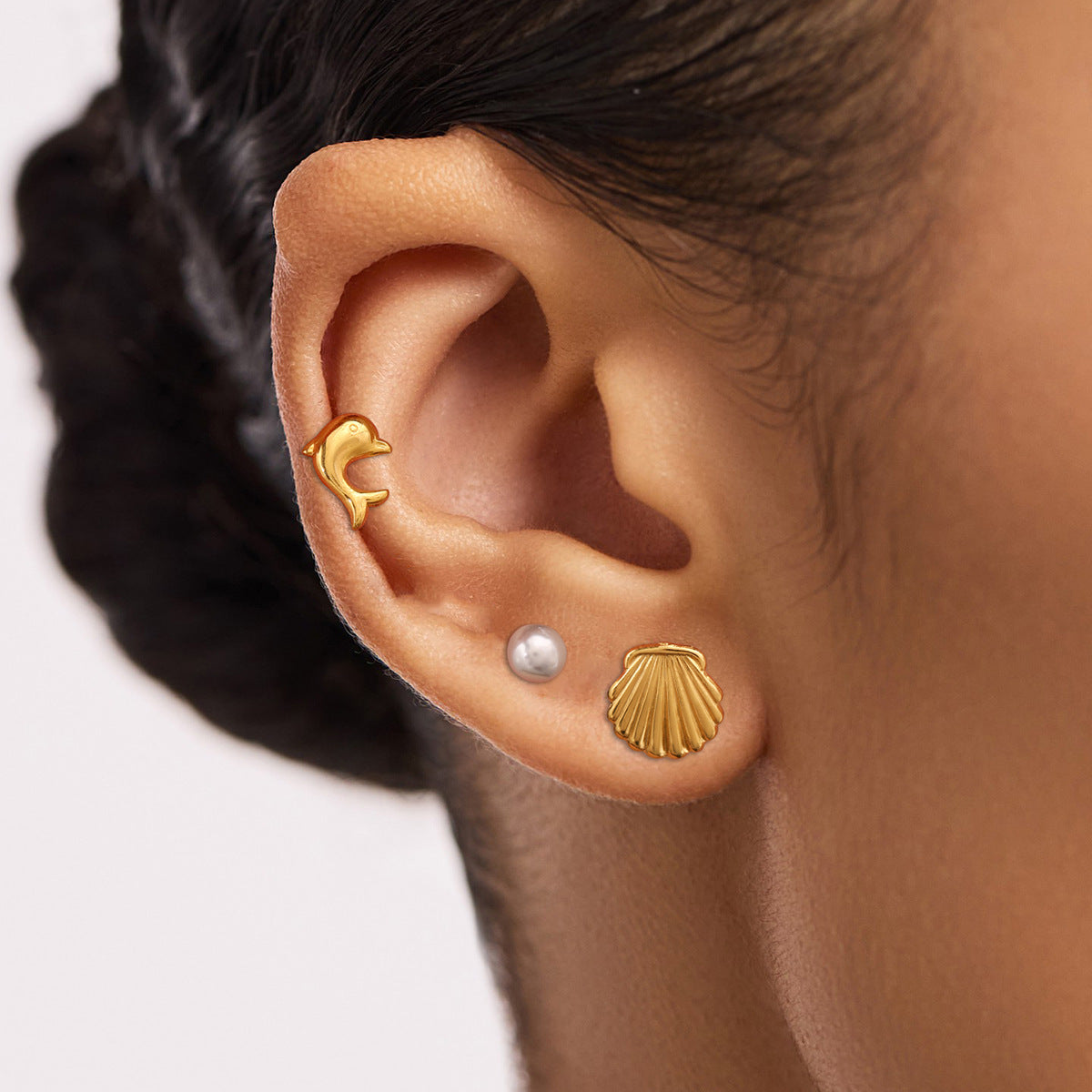 Gold seashell-shaped stud earrings for women, shell texture close-up on stone background