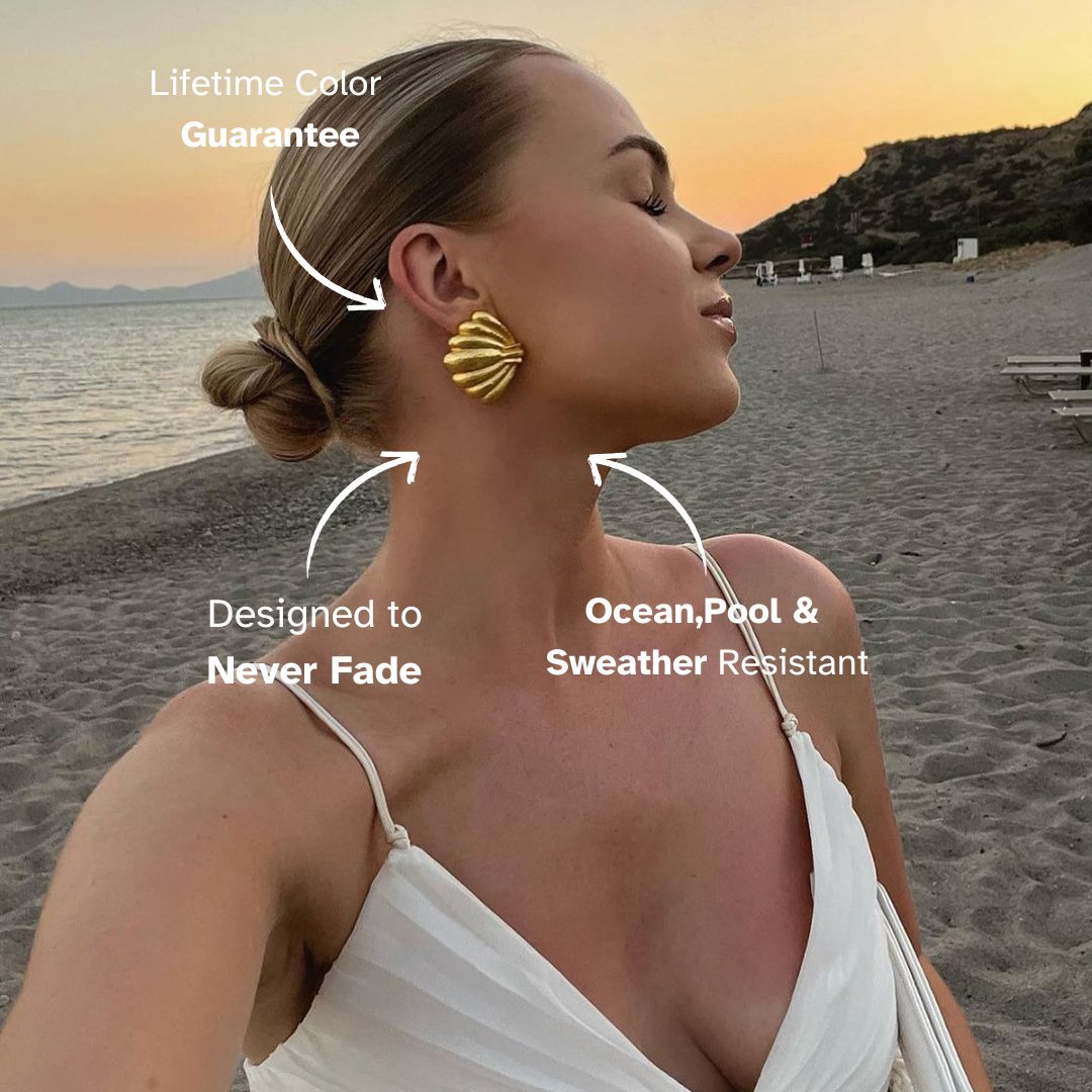 Beach sunset model wearing gold shell earrings with elegant white dress