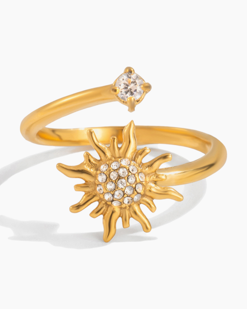 Gold ring with sun design and small gemstone on a white background