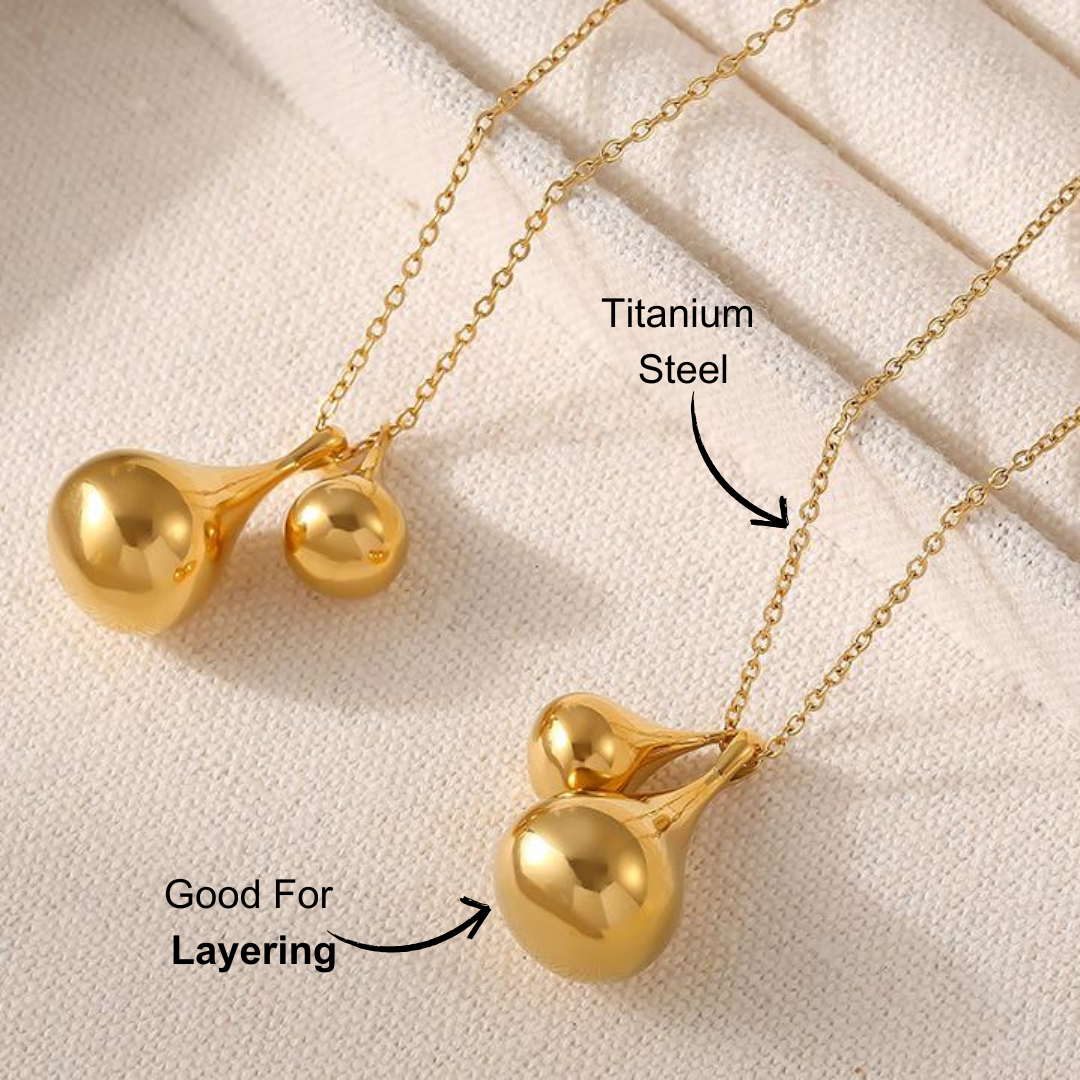 Close-up of a golden titanium plated necklace with a water droplet pendant