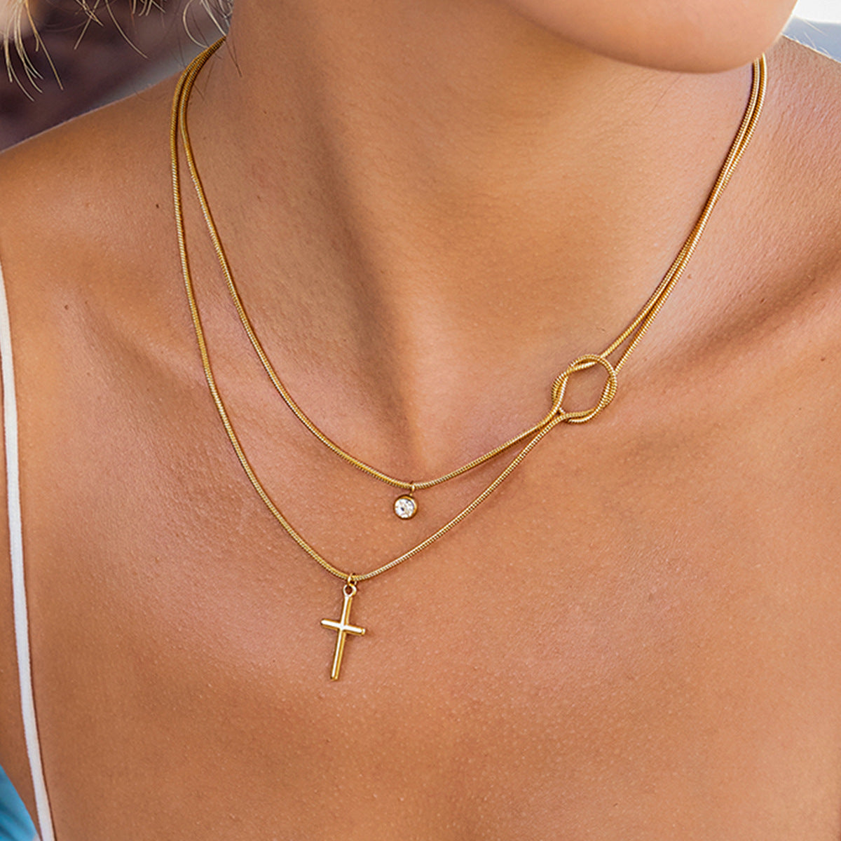Gold necklaces with a cross pendant and another pendant on a person's neck.
