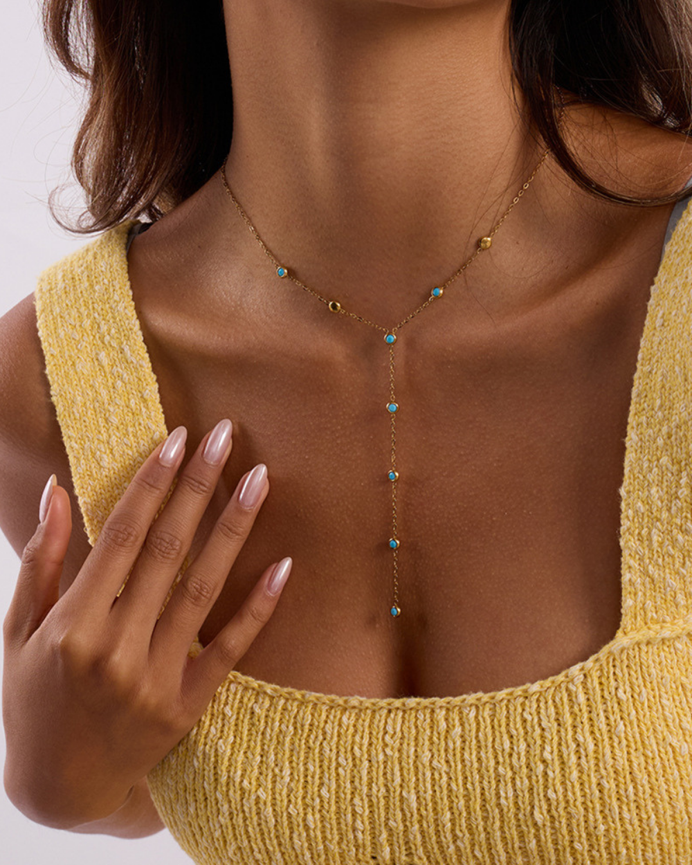Necklace with turquoise stones worn by a person in a yellow top
