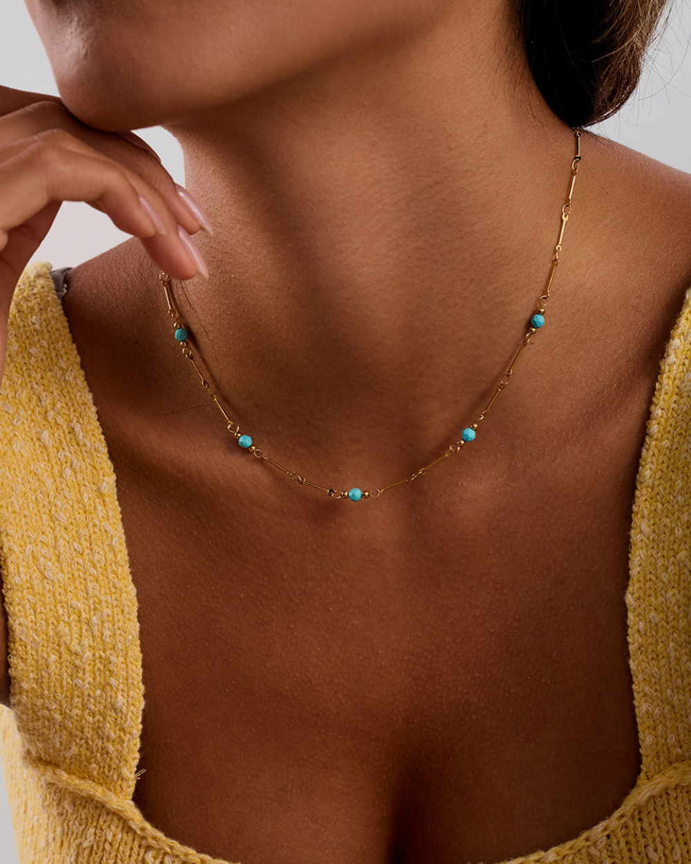 Necklace with turquoise beads worn by a person in a yellow top