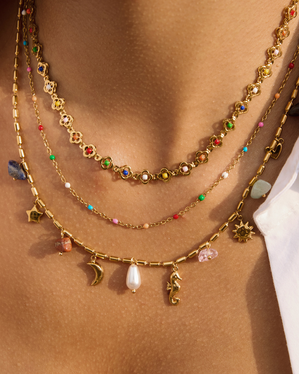 Gold necklaces with various charms on a person's neck
