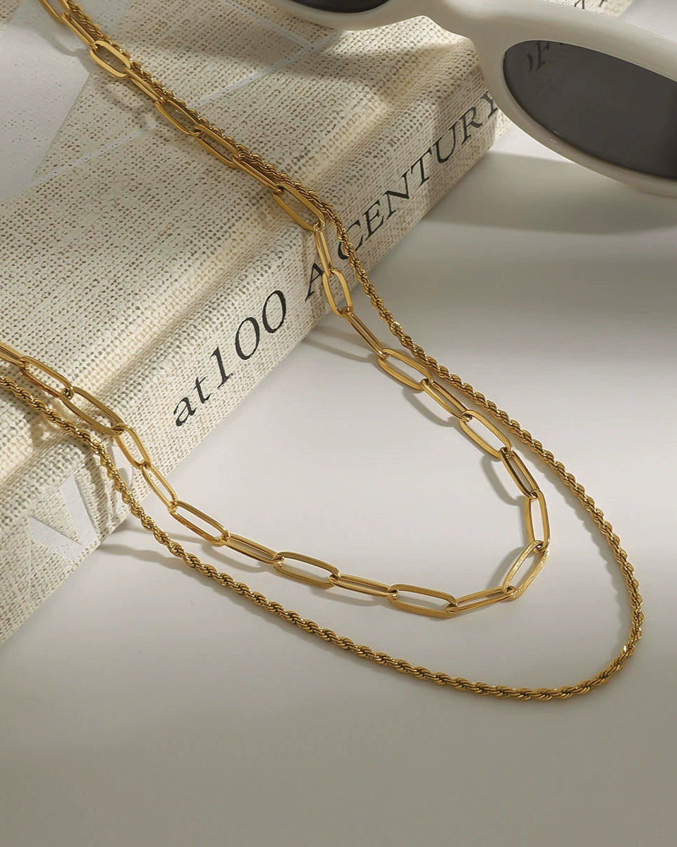 Gold chain necklace on a book with a white background