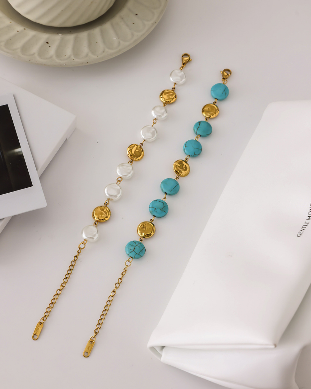 Pair of long earrings with gold, turquoise, and white beads on a light surface.