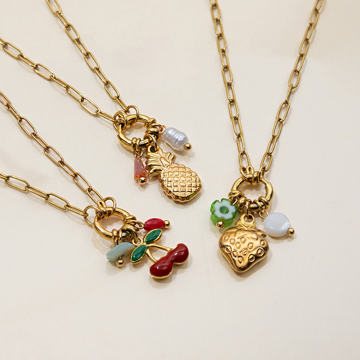 Three gold necklaces with various charms on a beige background