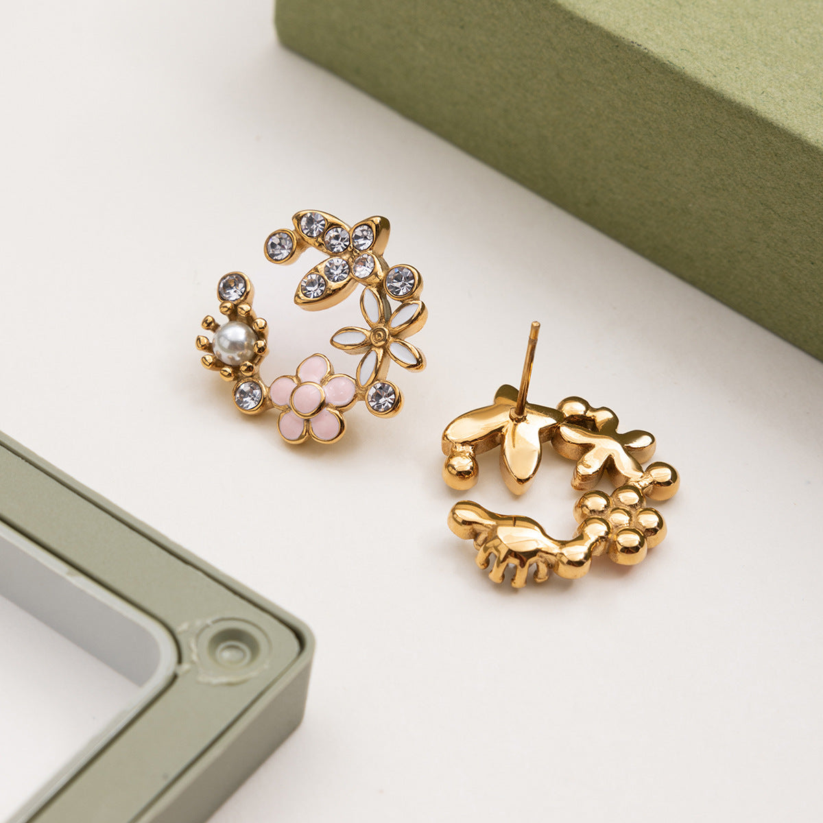 Gold earrings with floral and leaf designs on a light background