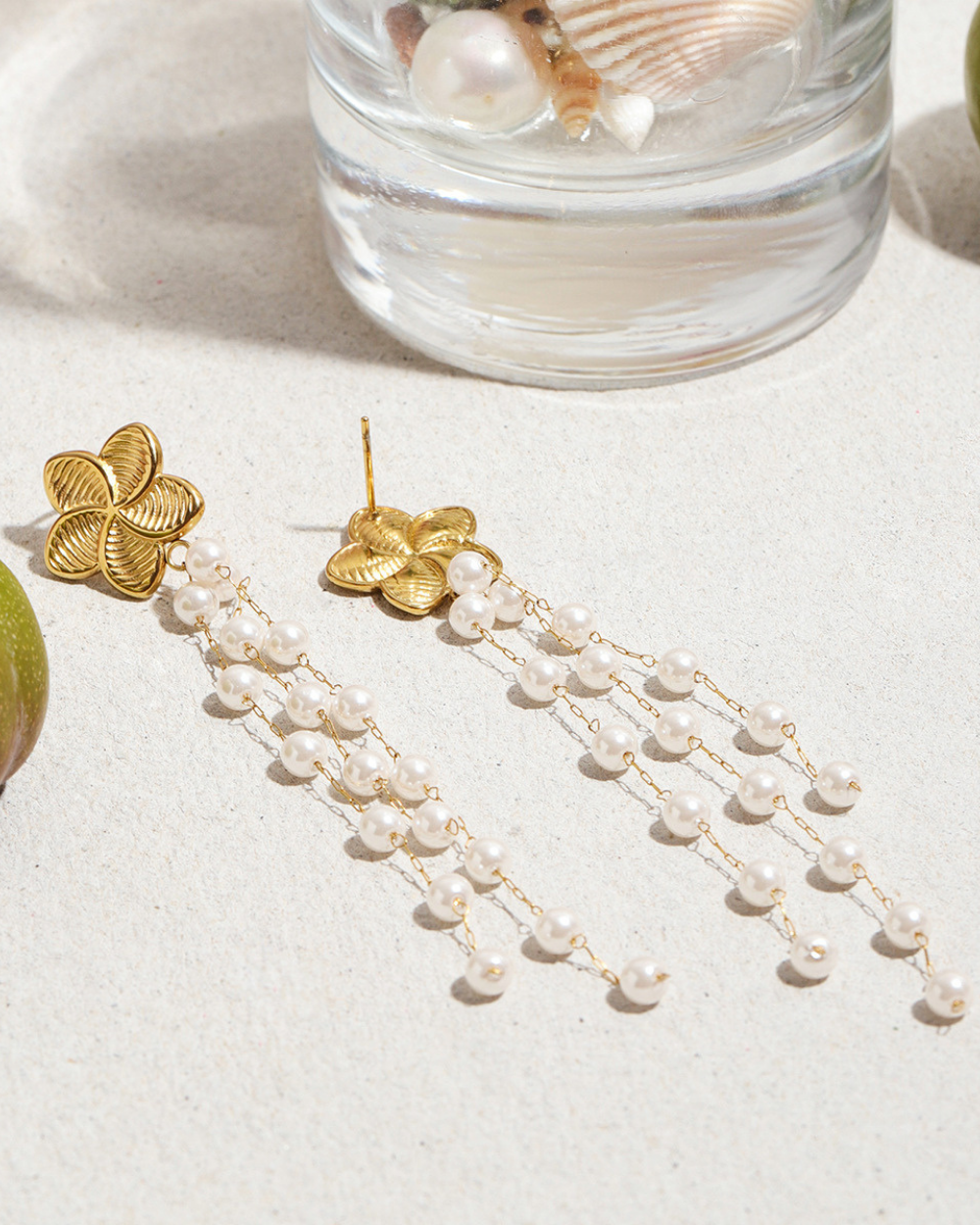 Gold earrings with pearl strands on a light surface