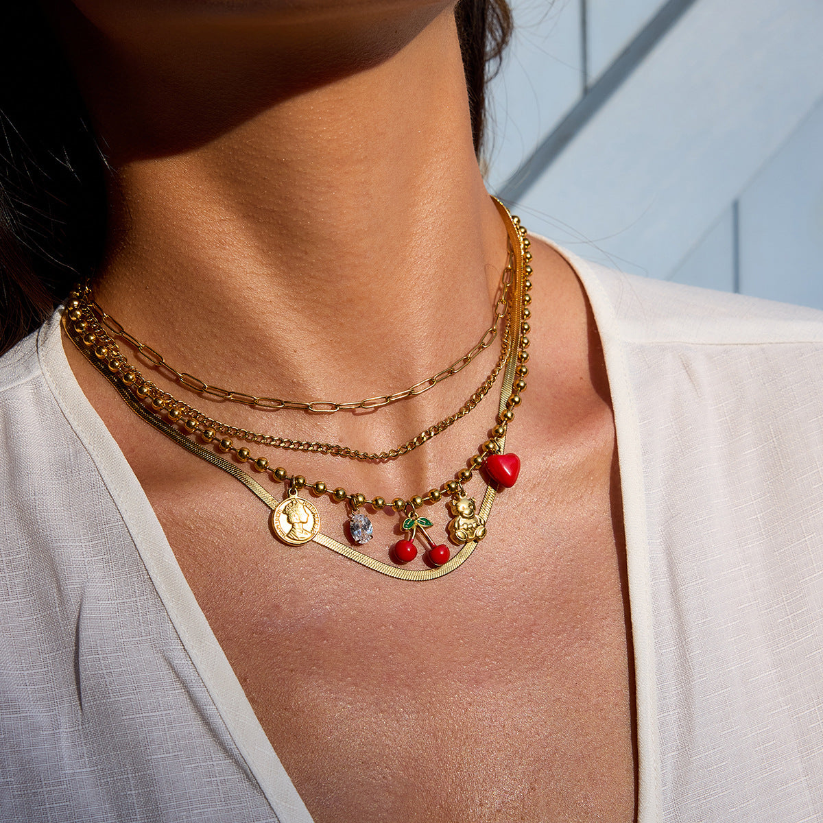 Layered gold chain necklace styled on model's neck in sunlight