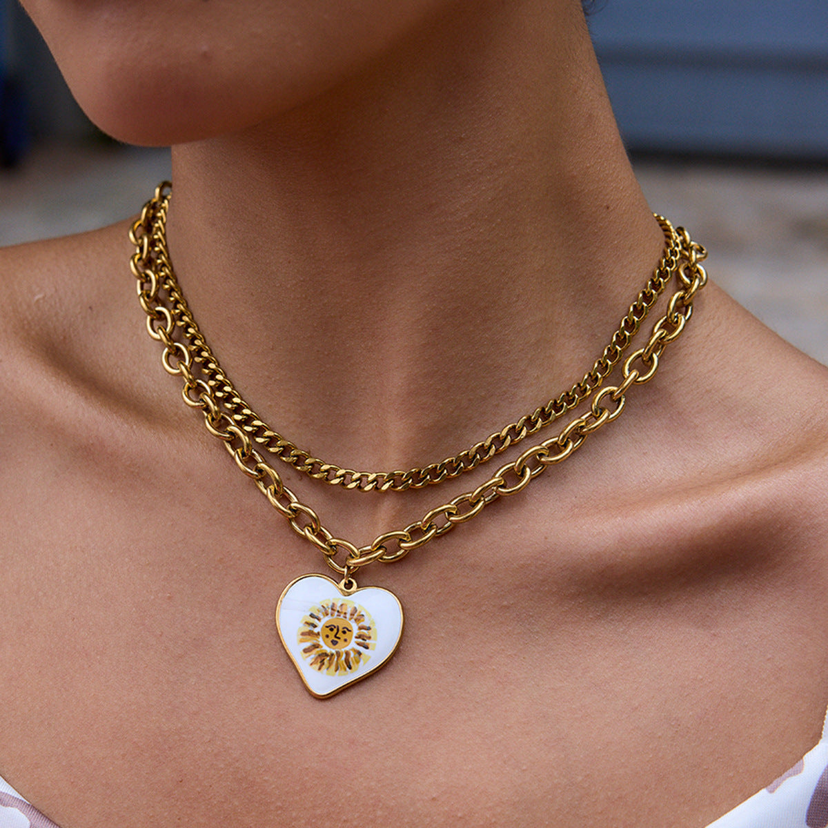 Two-layered gold chains with heart charm worn on sunlit neckline