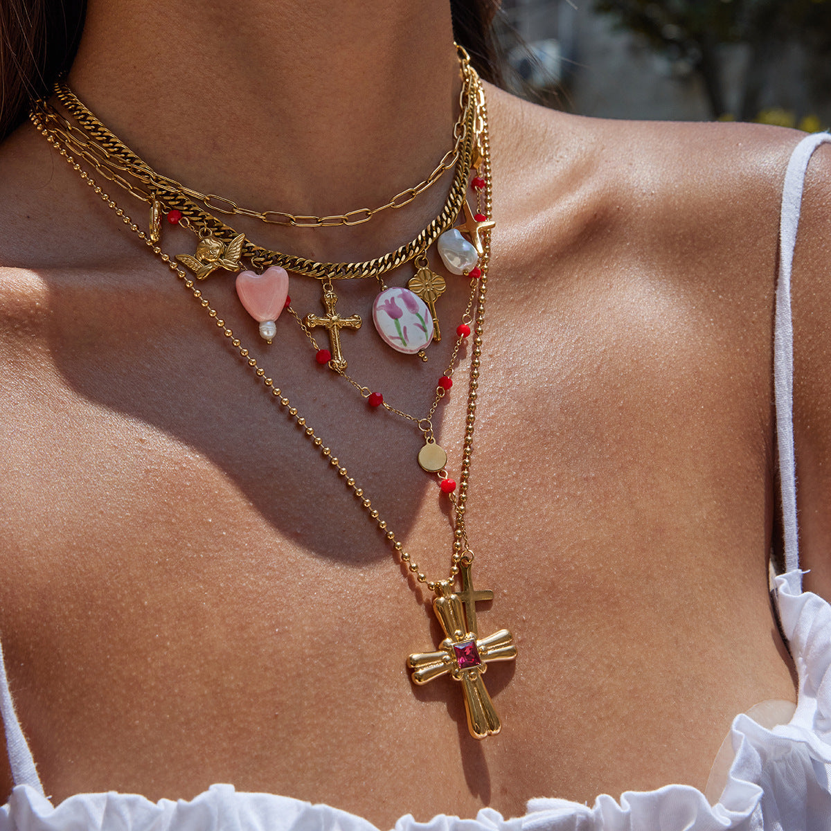 Styled photo of gold necklace with multiple pendants worn by woman in white top