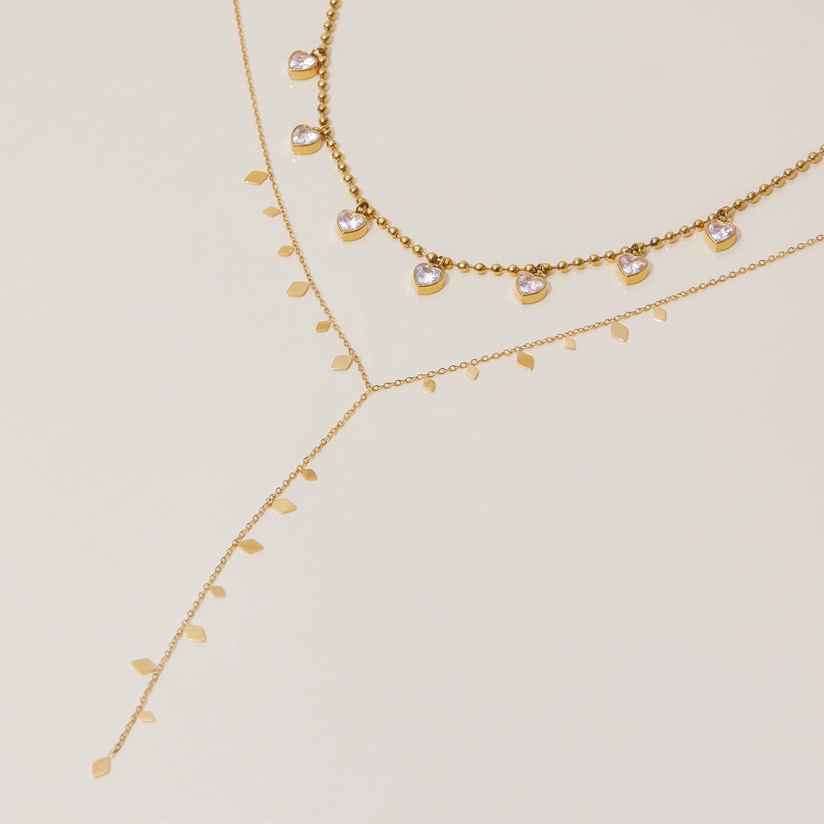 Trendy layered gold necklaces featuring heart charms and dainty leaf accents