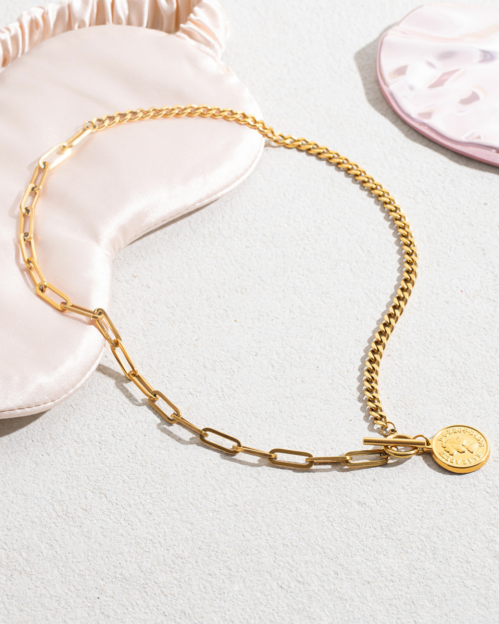 Gold chain necklace with a pendant on a light gray background