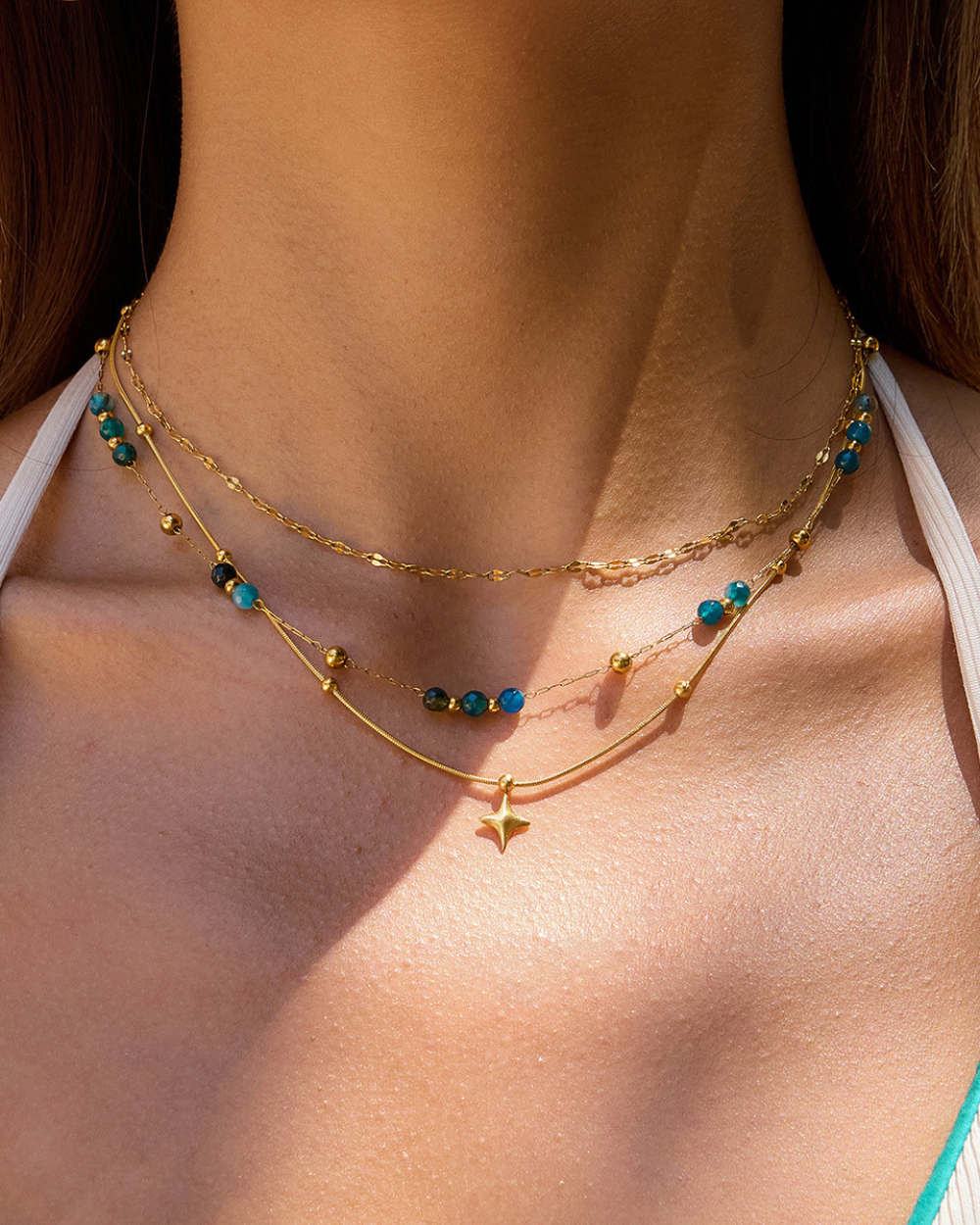 Gold necklace with blue beads on a person's neck
