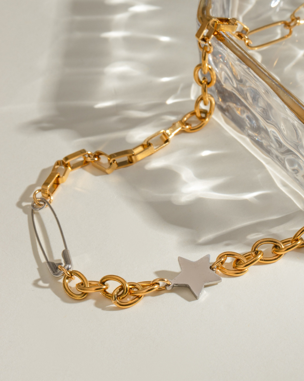 Gold chain bracelet with a star charm on a light background