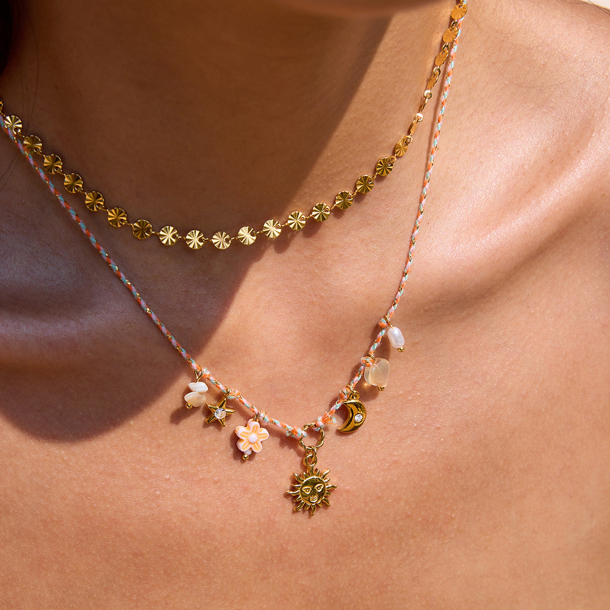 Model wears boho layered necklace with star, flower, and moon charms in natural sunlight