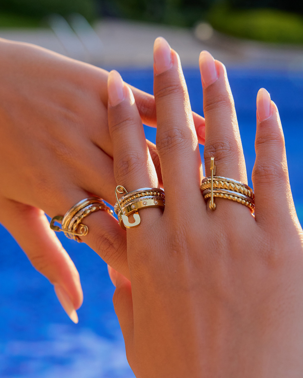 Close-up of hands wearing gold rings with a blurred blue background