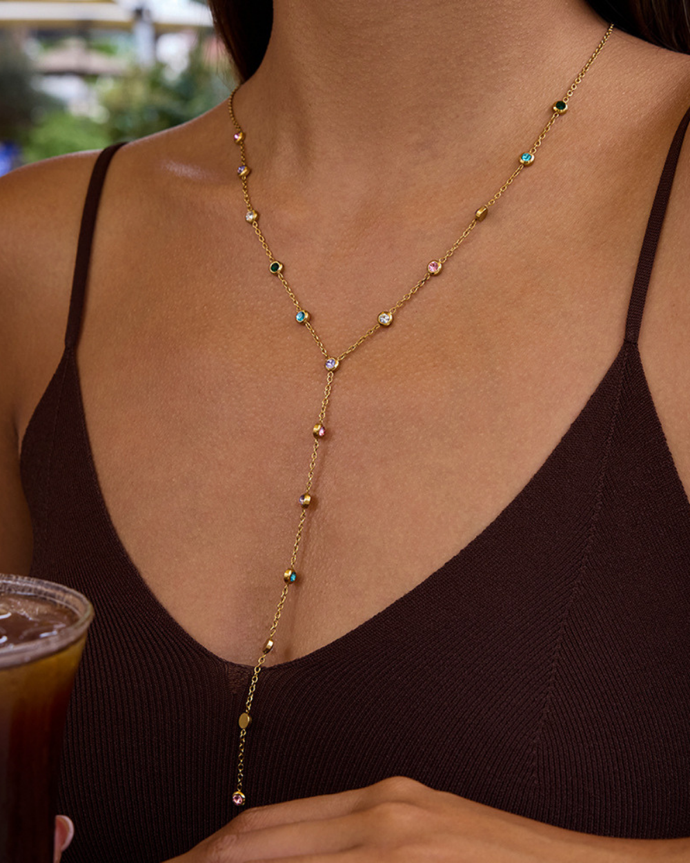 Gold necklace with small beads worn by a person in a dark top.
