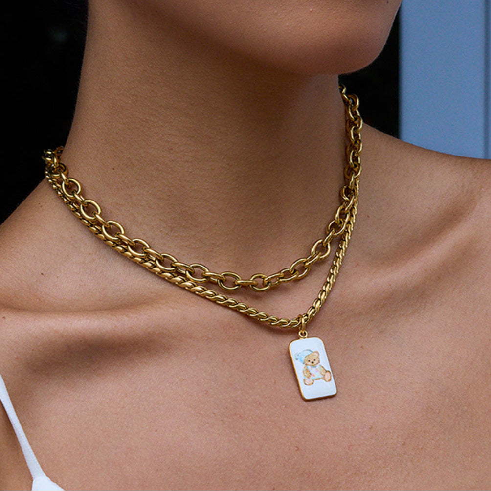 Model wearing teddy bear enamel necklace with stacked gold chains for Y2K vibe