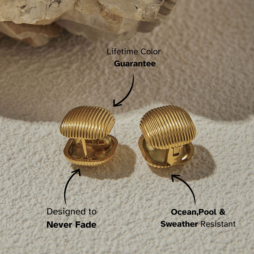 Square ribbed gold-tone clip-on earrings on sand-colored stone background