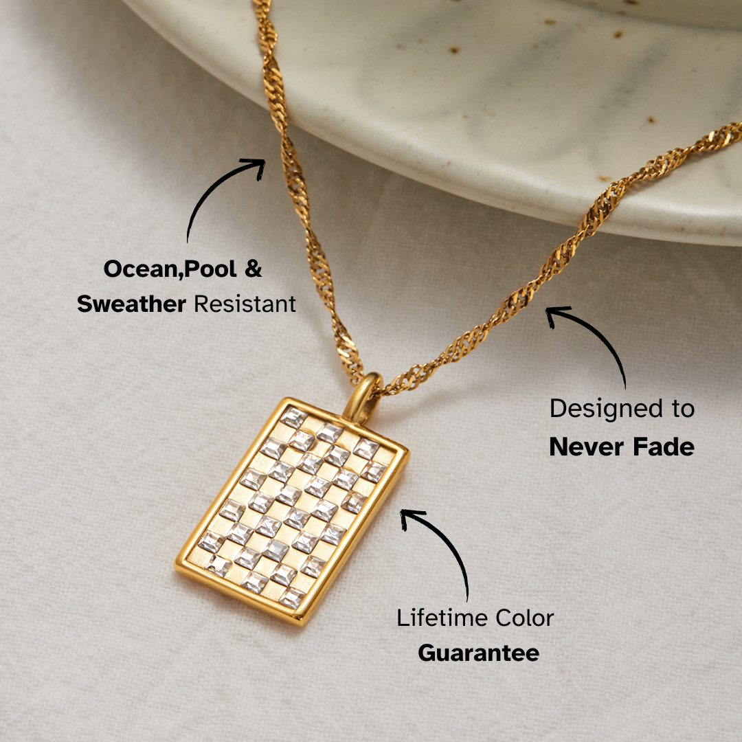 Full-length view of twisted gold chain and square pendant styled next to a ceramic dish.