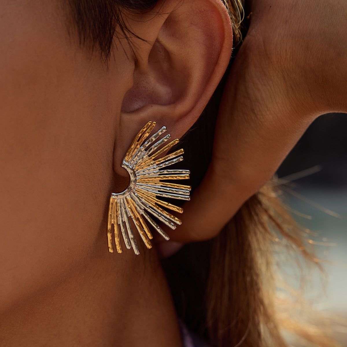 Model wearing two-tone fan earrings outdoors in natural light