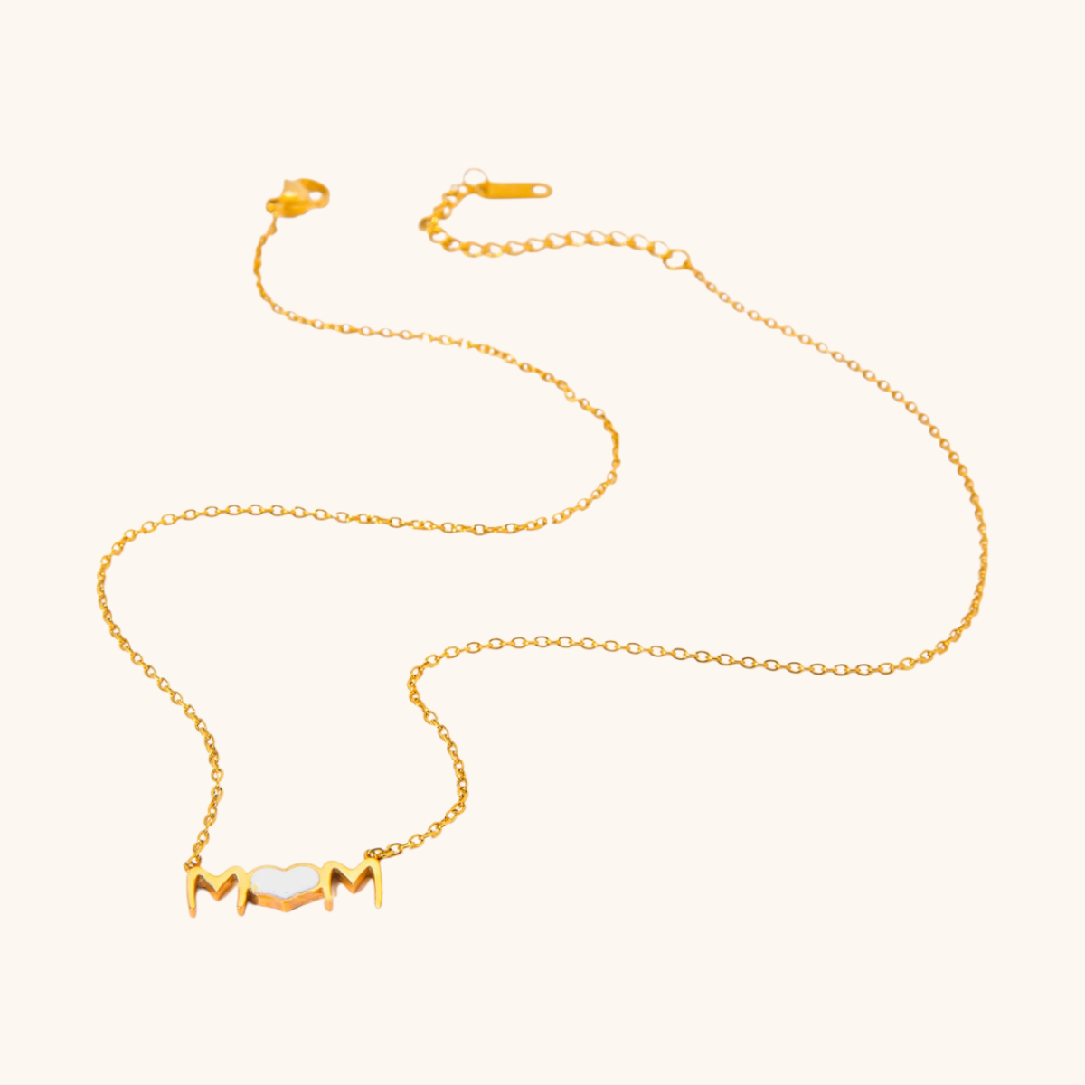 Gold mom heart necklace with white enamel, laid flat on white background