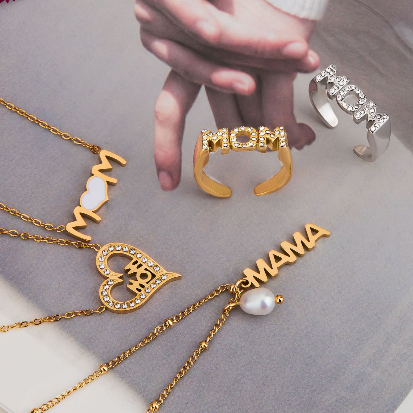 Flat lay of multiple mom-themed necklaces and rings with flowers, lifestyle scene