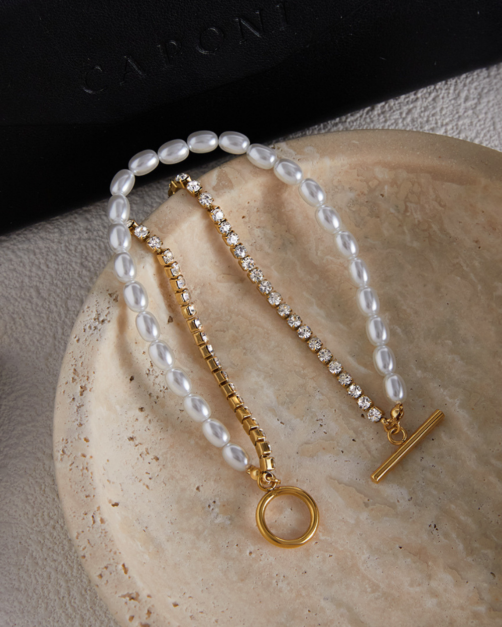 Pearl and gold bracelet on a textured surface with 'Cachet' branding.