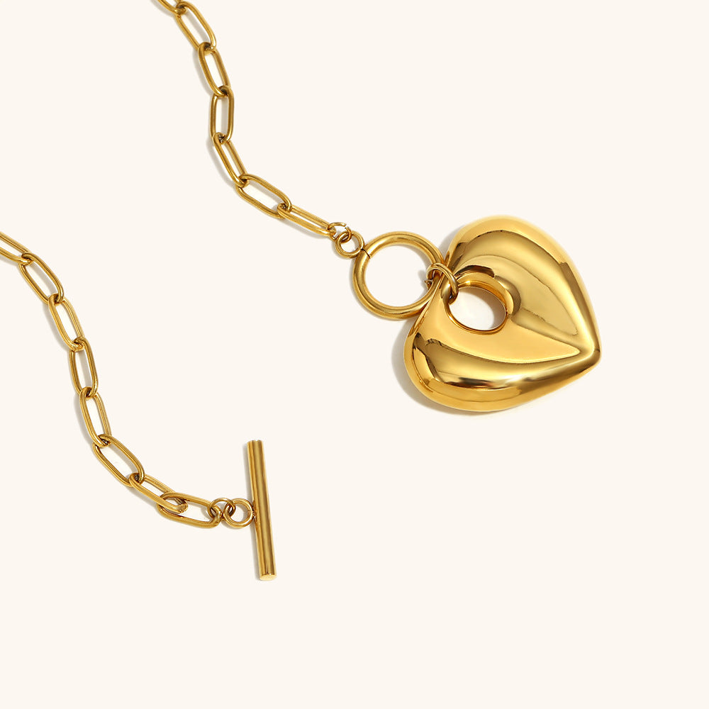 Gold heart necklace laid flat with open clasp, highlighting sleek chain and pendant design