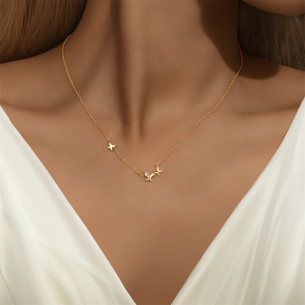 A model wearing a dainty butterfly charm necklace with gold plating.