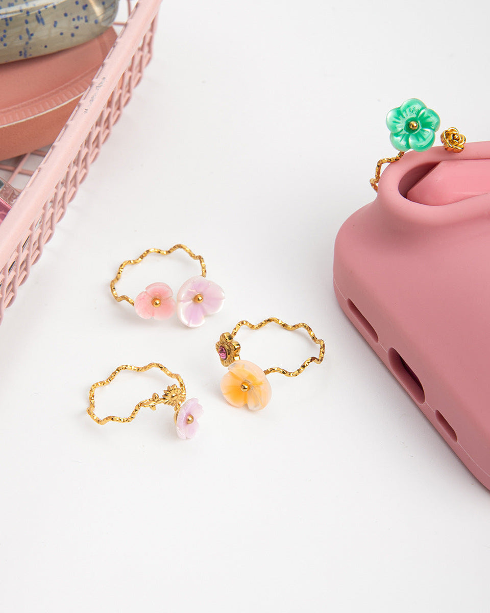 Set of floral phone charms on a pink phone case with a white background