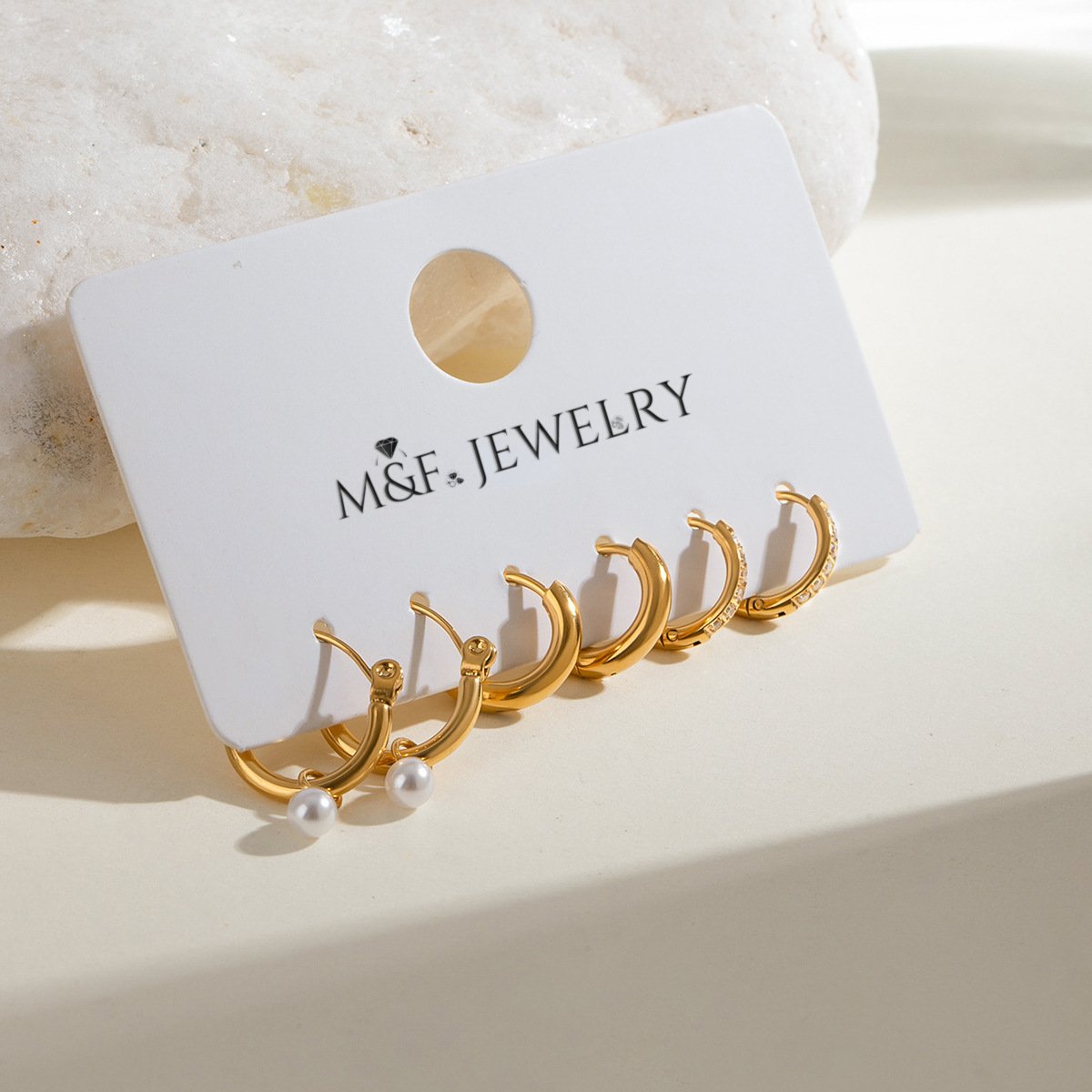 Stainless steel gold hoops displayed on white card, including pearl, plain, and cubic zirconia options