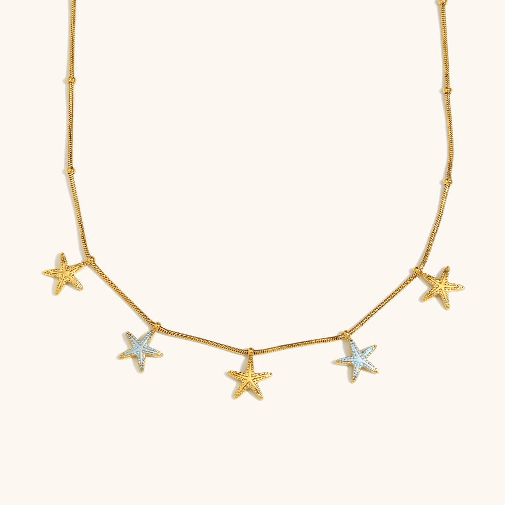 Gold chain necklace with dangling star charms on white background