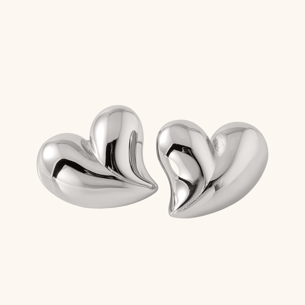 Simple silver heart earrings with reflective surface, soft light product display