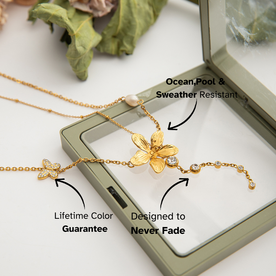 Gold necklace with butterfly design on a display card, featuring text about water resistance and color guarantee.