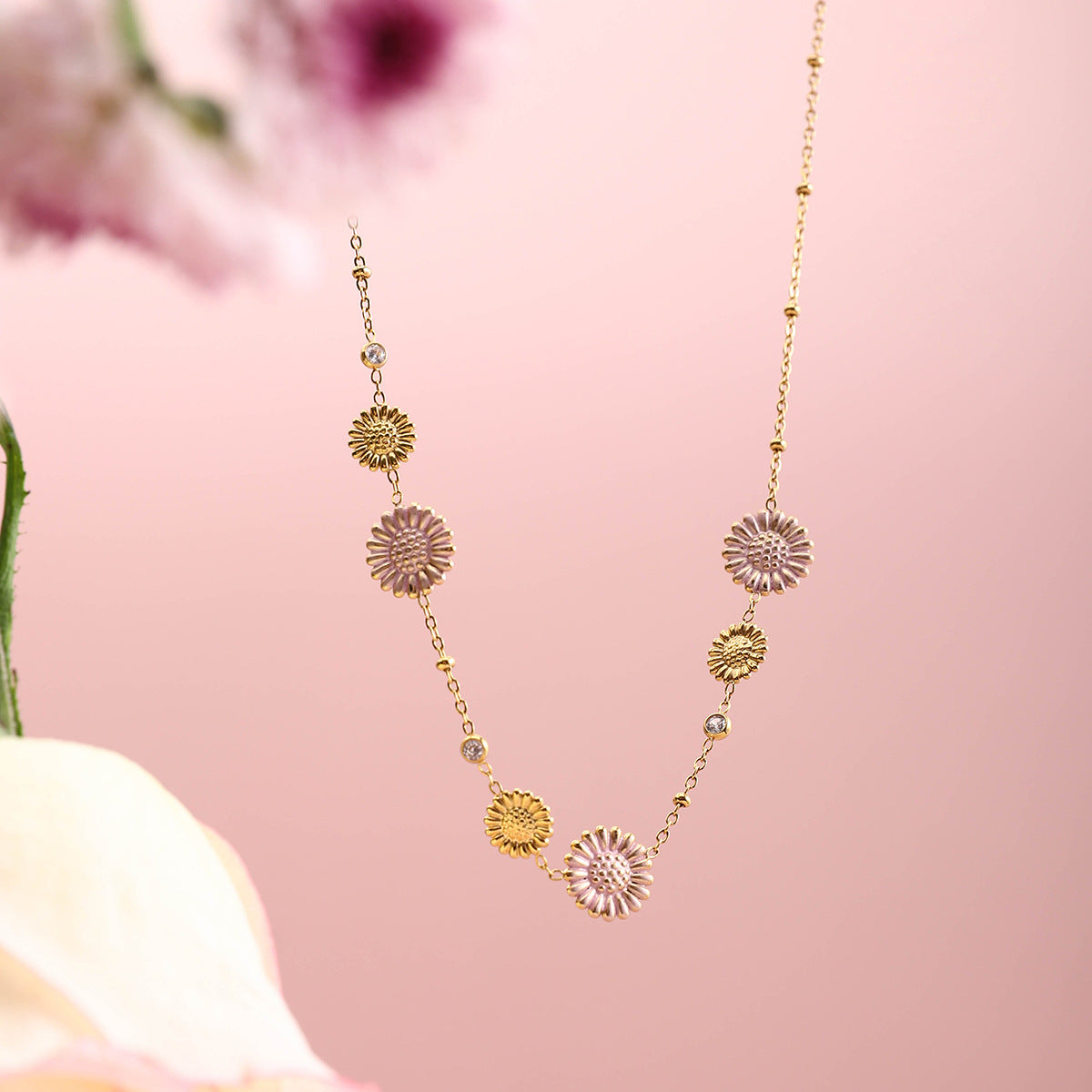 Zoomed-in view of dainty gold necklace with pink and gold daisies